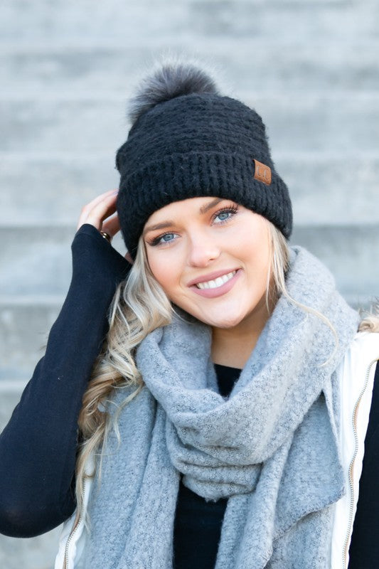 Smiling woman wearing Shophouse Northwest ultra soft fur pom beanie black knit with gray pom
