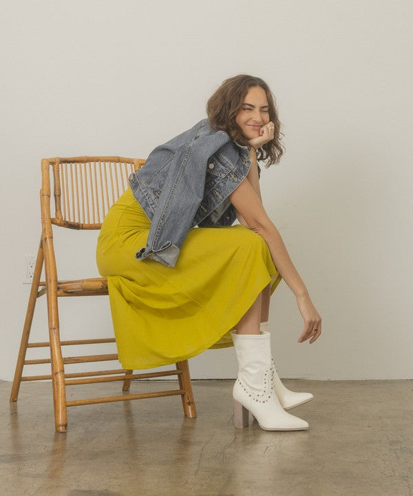 Shophouse Northwest white studded mid calf ankle boots worn by model with yellow dress and denim jacket seated