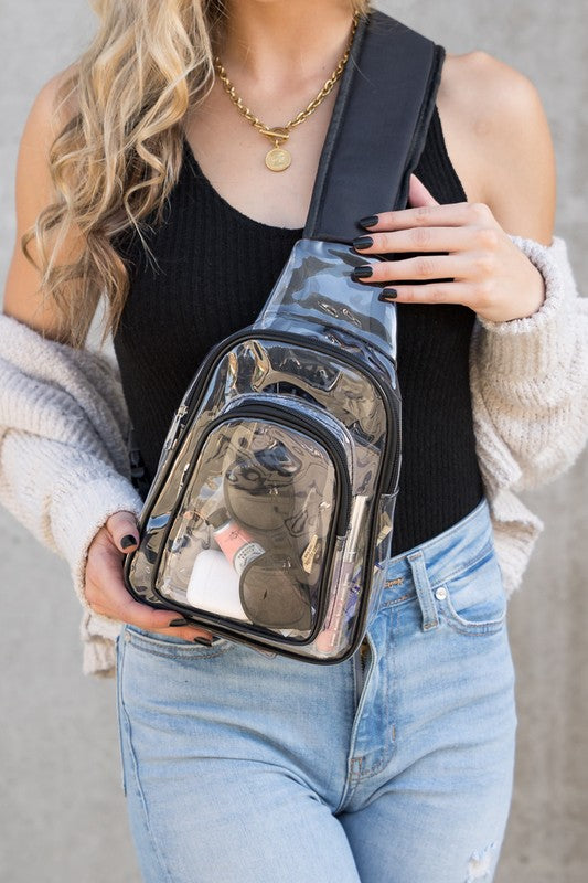 Shophouse Northwest clear stadium sling bag worn crossbody in tinted clear PVC showing sunglasses compact and lipstick