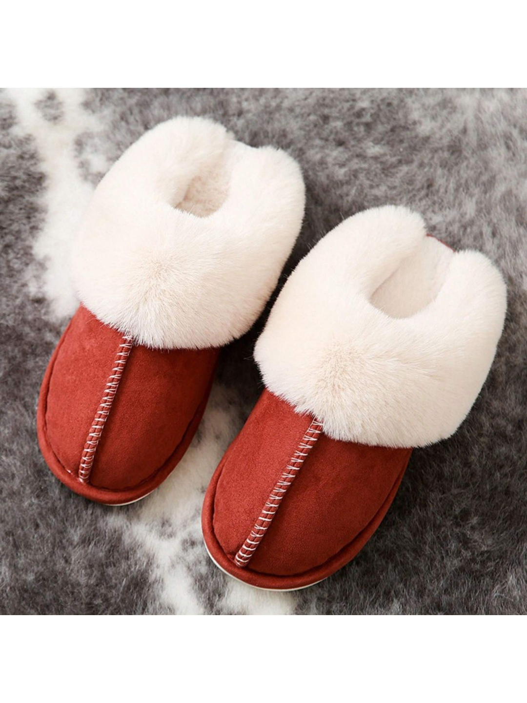 Pair of red slippers with white fur on a textured surface