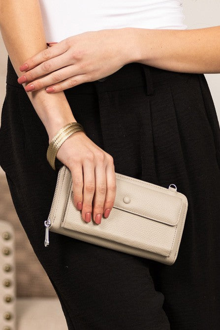 Shophouse Northwest beige wallet clutch held by woman featuring genuine leather phone wallet crossbody with zip closure