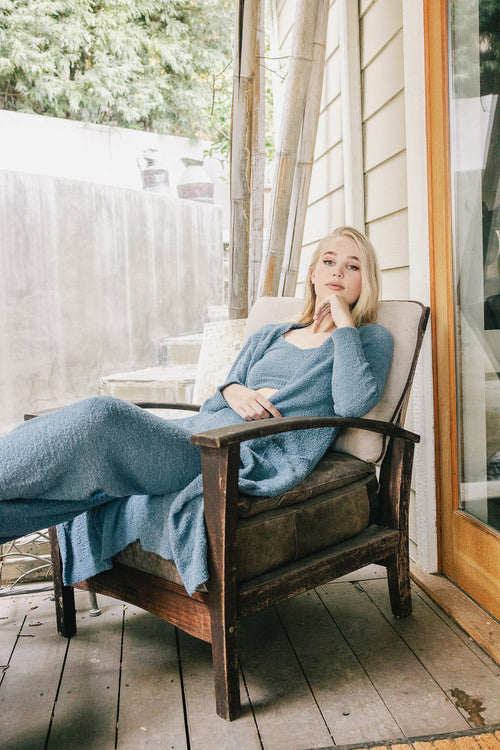 Model relaxing in boucle lounge pants and a cozy sweater on a wooden porch