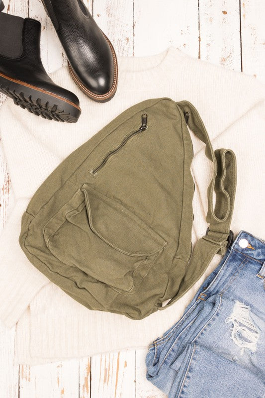 Shophouse Northwest oversized canvas sling bag in olive on sweater with boots and distressed jeans