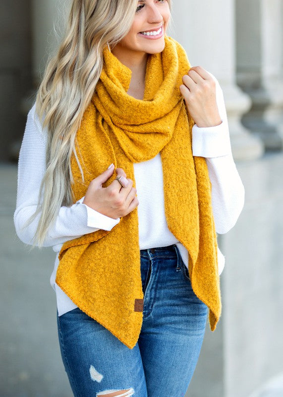 Woman wearing mustard yellow cc cozy draped oversized scarves for women over white sweater with distressed jeans