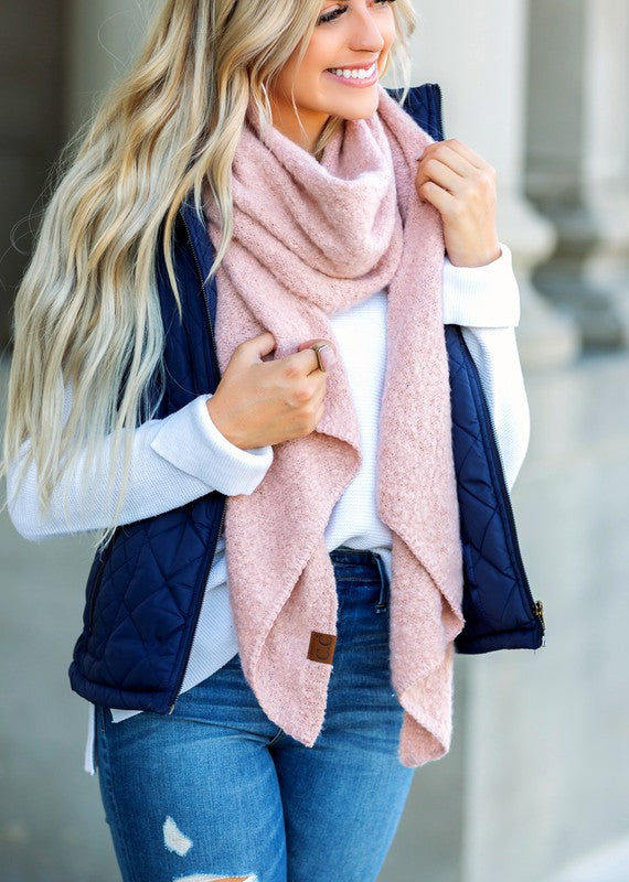 Blonde woman wearing pink cc cozy draped oversized scarves for women with navy quilted vest white sweater and distressed jeans