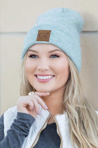 Smiling woman wearing CC heathered boyfriend beanie in light blue with leather CC patch casual cold weather style