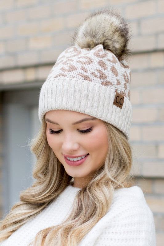Shophouse Northwest cream leopard fur knit pom beanie with ribbed cuff and faux fur pom on model