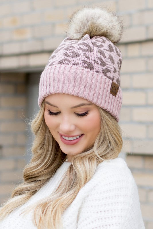 Shophouse Northwest leopard fur knit pom beanie dusty pink leopard pattern faux fur pom and cuff label on smiling model