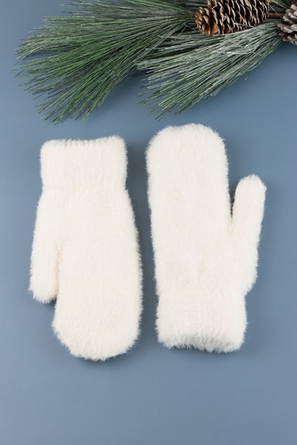 Shophouse Northwest cream plush fur lined mittens pair on blue background with pine branch holiday styling