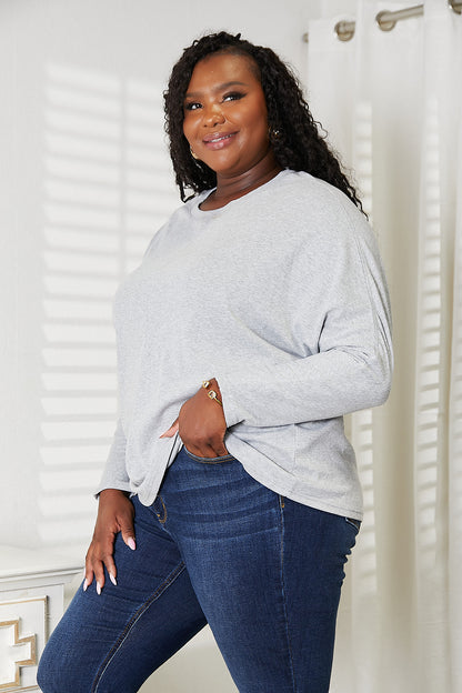 Plus-size model wearing a light gray double take seam detail top with a relaxed fit and casual style