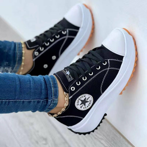 Trendy flat lace-up canvas sneakers in black with contrast white toe cap and orange outsole