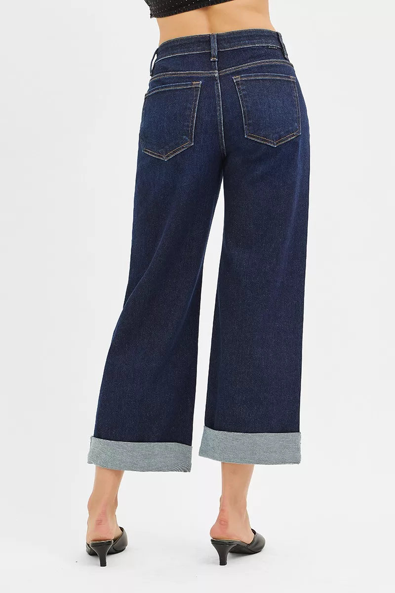 Back view of mid rise ankle wide leg roll up jeans featuring a dark wash and wide cuff