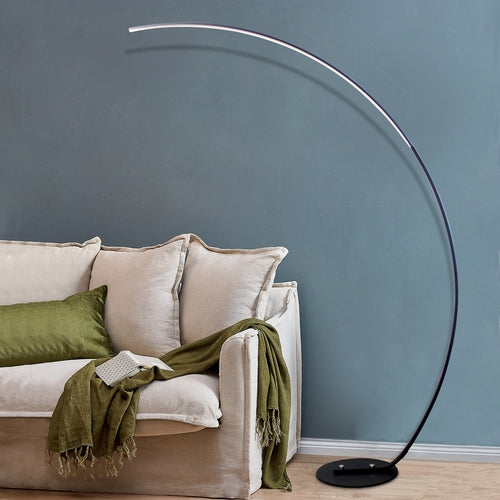 Modern curve floor lamp with sleek design next to a cozy couch for stylish home lighting
