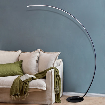 Modern curve floor lamp with sleek design next to a cozy couch for stylish home lighting