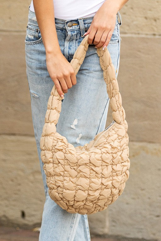 Shophouse Northwest beige quilted puffer shoulder bag held by woman with jeans ideal everyday carry