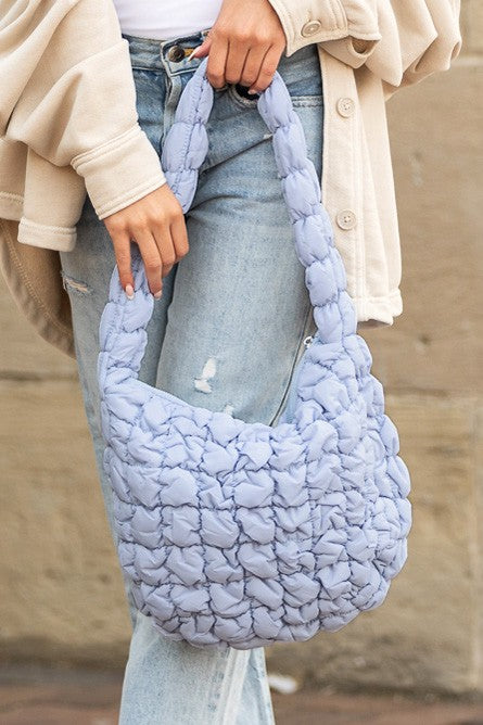Shophouse Northwest light lavender quilted puffer shoulder bag with braided strap worn with jeans