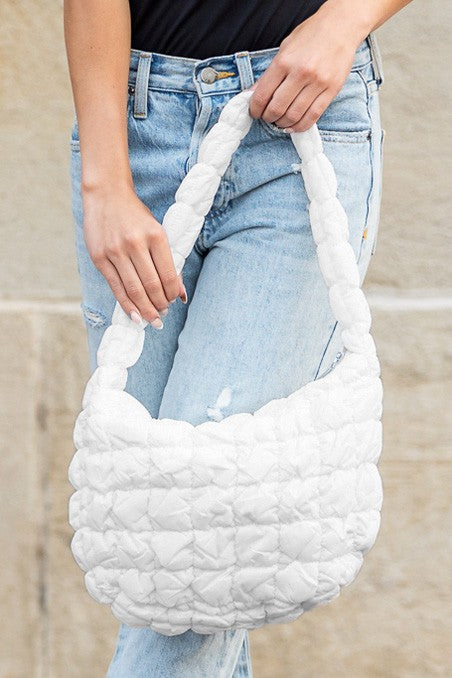 White quilted puffer shoulder bag by Shophouse Northwest held by model with jeans padded soft design