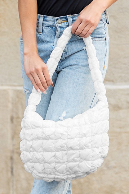 White quilted puffer shoulder bag by Shophouse Northwest held by model with jeans padded soft design