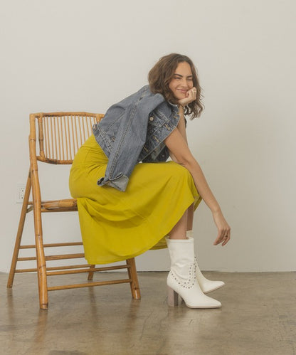Shophouse Northwest white studded mid calf ankle boots worn by model with yellow dress and denim jacket seated