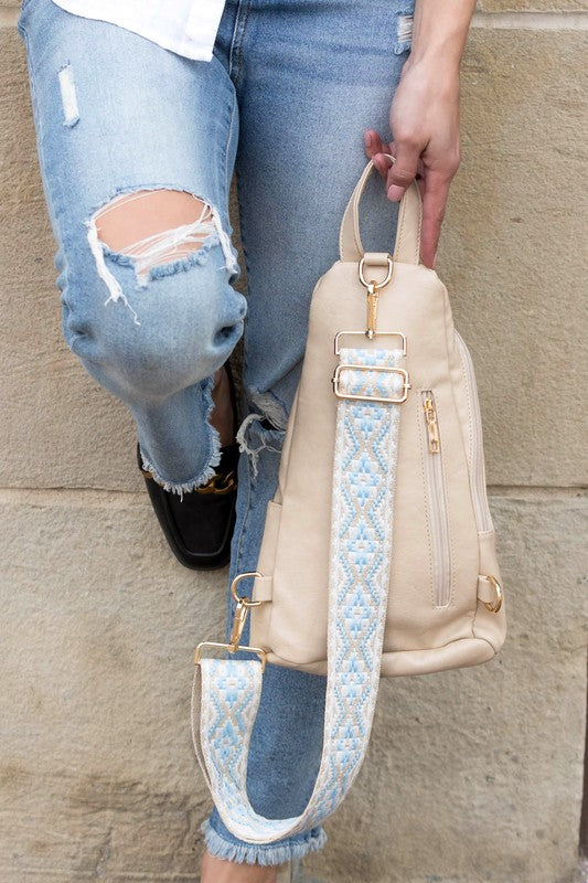 Beige sling bag with blue embroidered strap and gold hardware worn with ripped jeans everyday sling bag for women
