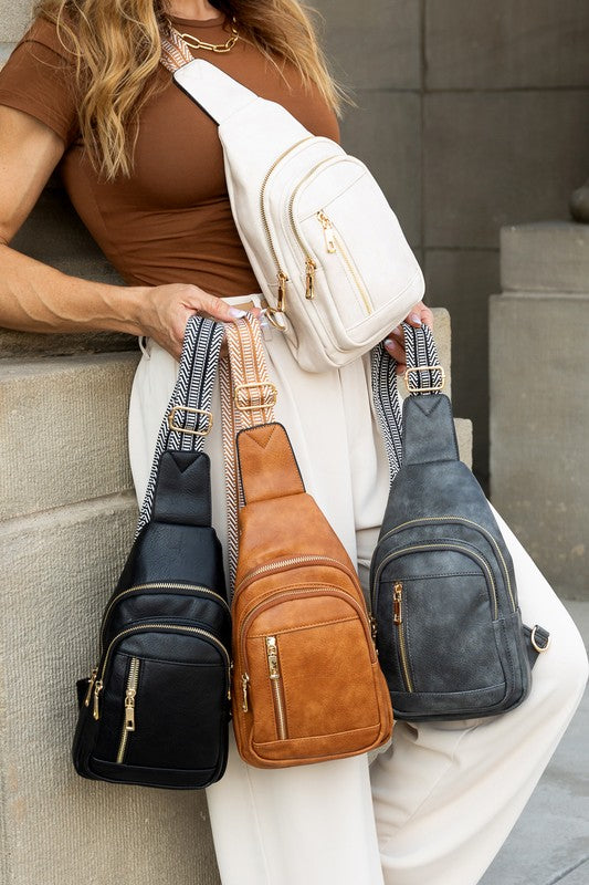Model wearing Genevive leather sling crossbody bag in white while holding black tan and gray color options