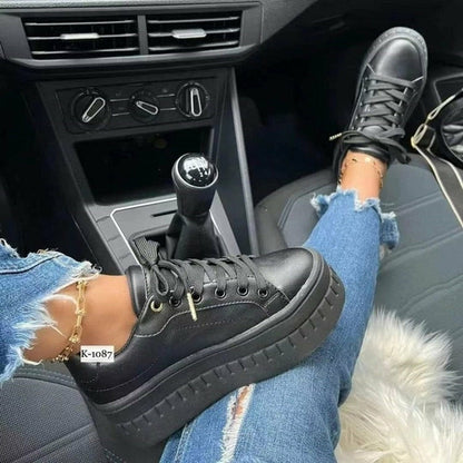 Stylish women platform sneakers in black worn with ripped jeans in a car interior