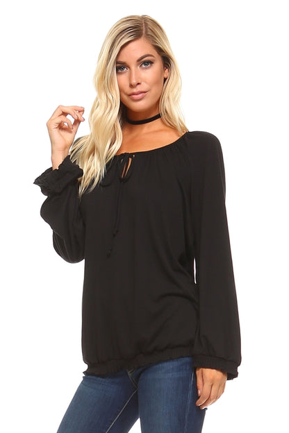 Model wearing a black women's long sleeve peasant top with tie neck and ruffled cuffs